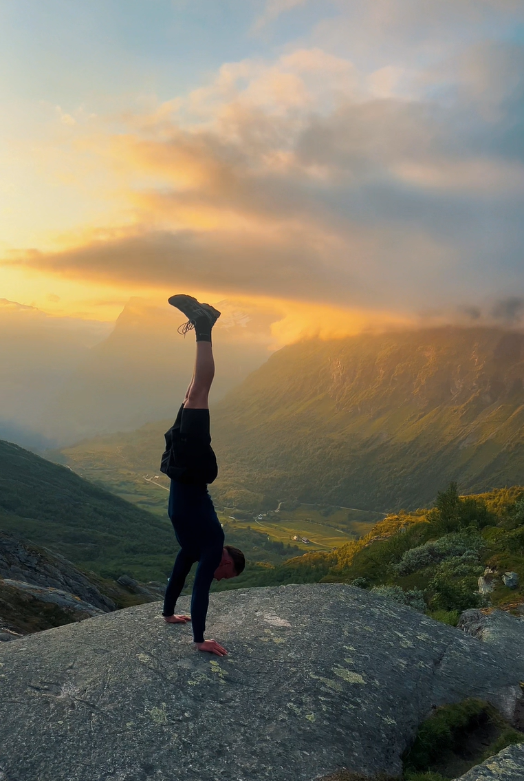 Coach holding a handstand on a mountain